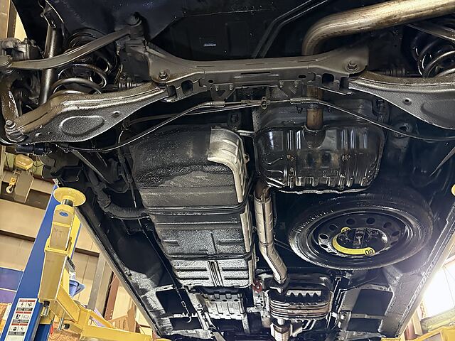 Underside of a car on the lift: suspension, exhaust and fuel tank in view