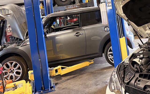 Clean grey Mini parked beside a lift in the Kingdom Auto shop